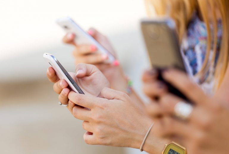 Portrait of three girls chatting with their smartphones at the park