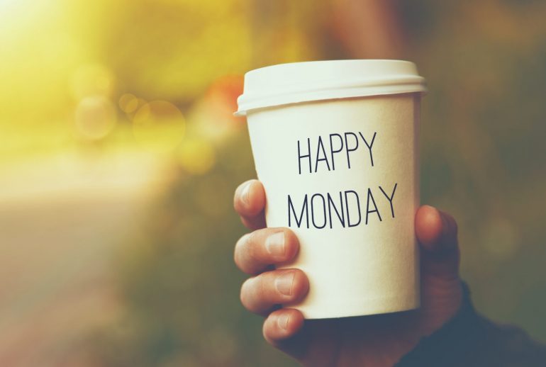 hand holding paper cup of coffee with Happy Monday motivational text on natural morning background