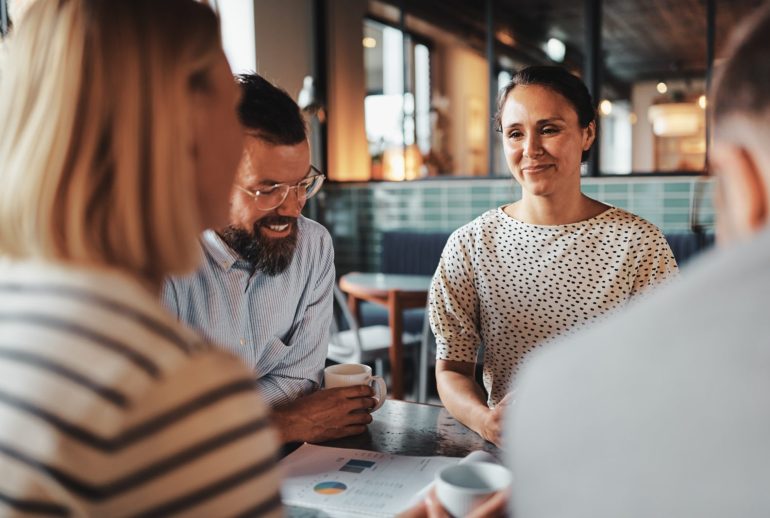 Smiling,Young,Businesswoman,Talking,With,A,Group,Of,Colleagues,Over