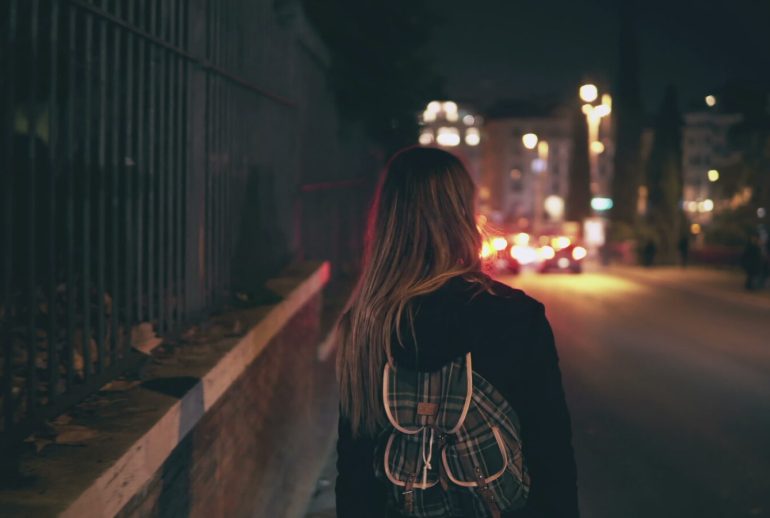 Back,View,Of,Brunette,Woman,Walking,Near,The,Road,At